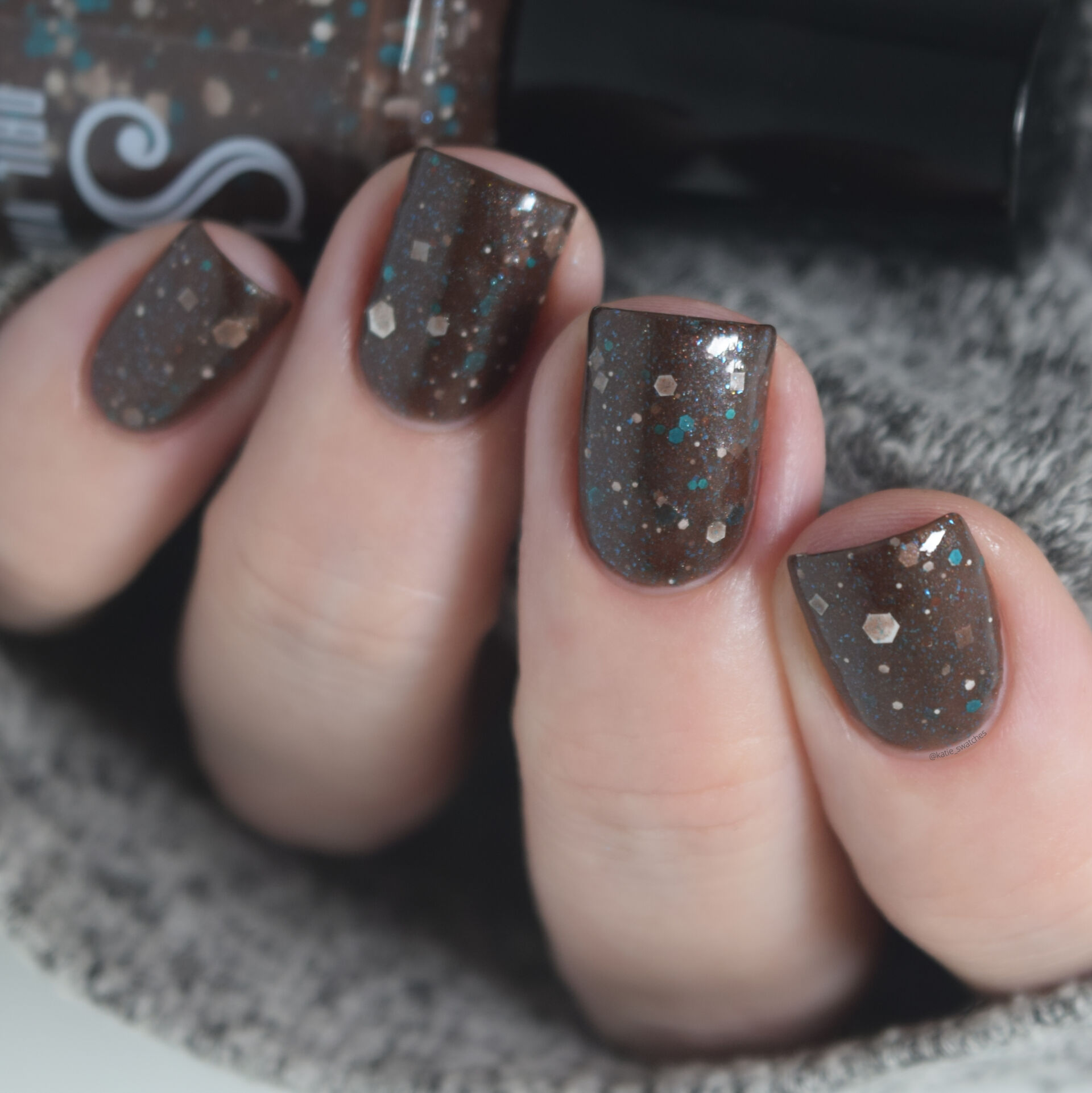 Scofflaw Nail Varnish Jackalope nail polish is a brown crelly with white and turquoise glitter in different shapes and sizes