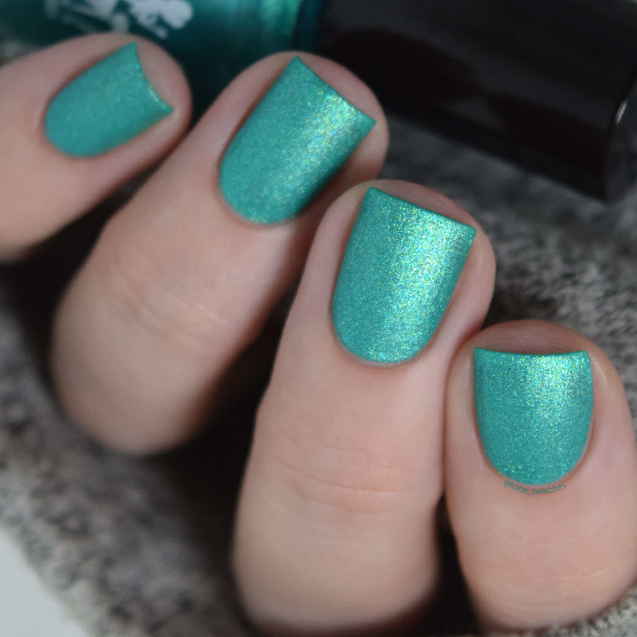 Girly Bits - Cross-Eyed Bear nail polish swatch. Caribbean green matte nail polish with a gold/blue shimmer.